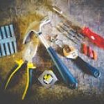 Collection of hand tools including hammer, screwdriver, and pliers in a workshop setting.
